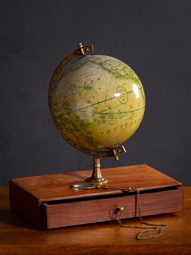 Mappemonde et loupe sur rangement bois et tiroir